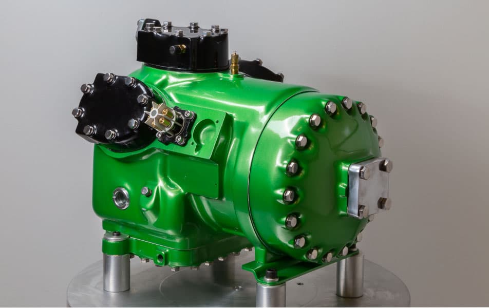New CMP scroll compressor in signature green finish, staged on a shop stand for commercial HVAC and refrigeration service